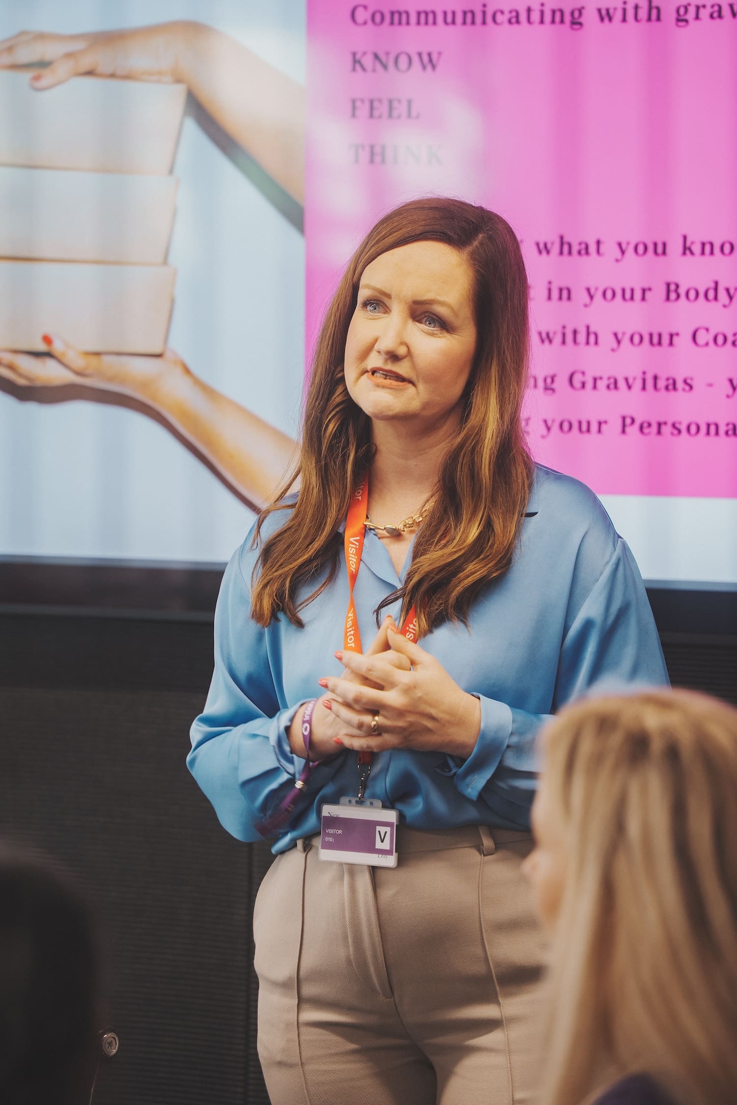 woman in blue shirt speaking in front of her presentation